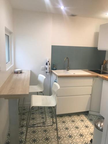 cocina con 2 sillas blancas y lavamanos en LA PETITE COUR, en Loches