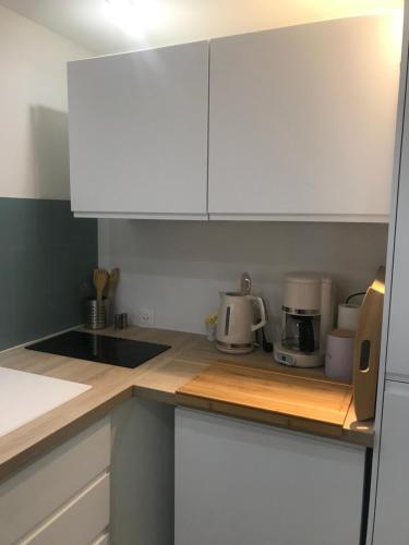 une cuisine avec des armoires blanches et un comptoir dans l'établissement LA PETITE COUR, à Loches