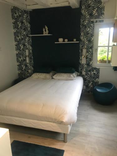 um quarto com uma cama branca e uma parede preta em LA PETITE COUR em Loches