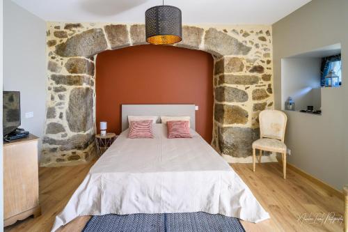 a bedroom with a bed with a stone wall at La Fournial in Lunac