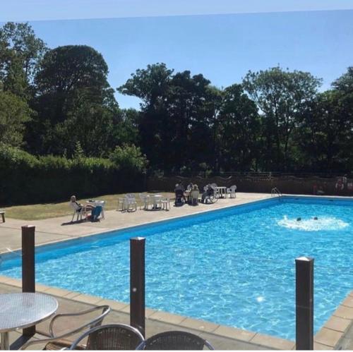 a large blue swimming pool with people sitting around it at SNOWDON LODGE - GLAN GWNA HOLIDAY PARK CAERNARFON - Luxury Family Lodge in Caernarfon