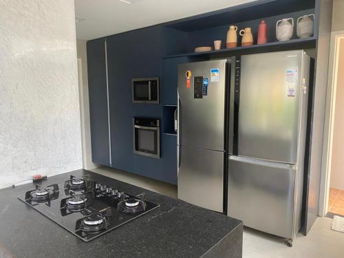 cocina con fogones y nevera de acero inoxidable en Casa maravilhosa na praia de Muro Alto - Porto de Galinhas, en Porto de Galinhas