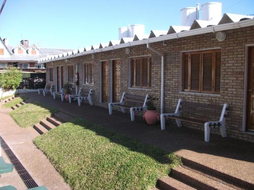 a row of benches in front of a brick building at Bungalows Archi in Termas del Daymán