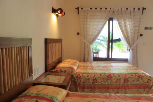 Un dormitorio con dos camas y una ventana. en Hotel Villa Kiin, en Isla Mujeres