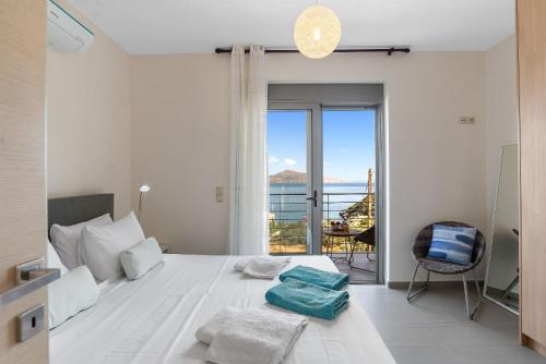 a white bedroom with a bed and a balcony at Almyrida Panorama II BY APOKORONAS-VILLAS in Almirida