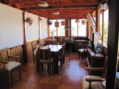 un comedor con mesas, sillas y ventanas en Hostal Antumulen en Pichilemu