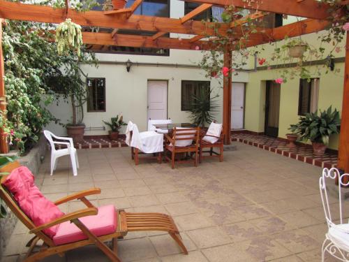 a patio with chairs and a table and a pergola at Hostal Antumulen in Pichilemu