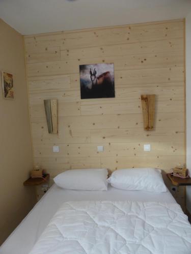 1 dormitorio con cama blanca y pared de madera en APPARTEMENT PUY SAINT VINCENT ALPES DU SUD été - hiver en Puy-Saint-Vincent