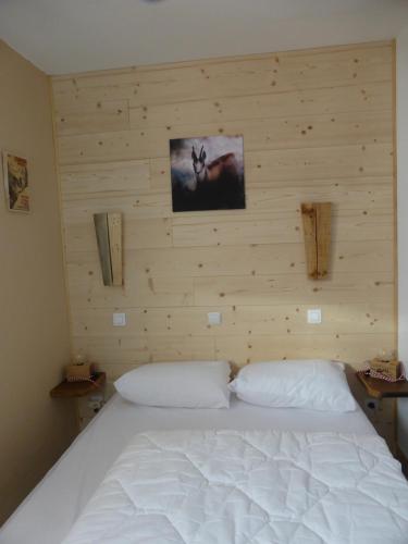 a bedroom with a white bed with a wooden wall at APPARTEMENT PUY SAINT VINCENT ALPES DU SUD été - hiver in Puy-Saint-Vincent
