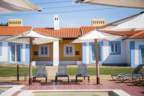 a group of chairs and umbrellas in front of a house at Monte do Giestal - Casas de Campo & Spa in Abela