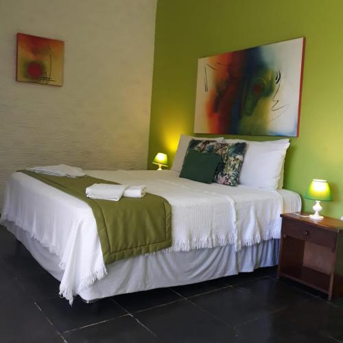 a bedroom with a large white bed with a painting on the wall at Pousada Vila do Sol in Búzios
