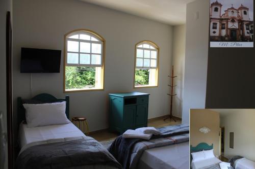 een slaapkamer met 2 bedden en 2 ramen bij Vila Marias in Ouro Preto