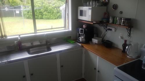 a kitchen with a sink and a microwave and a window at Little Red Riding Hood in Reefton