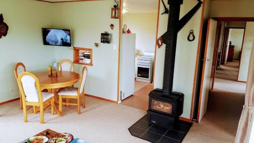 a living room with a wood stove and a table at Little Red Riding Hood in Reefton