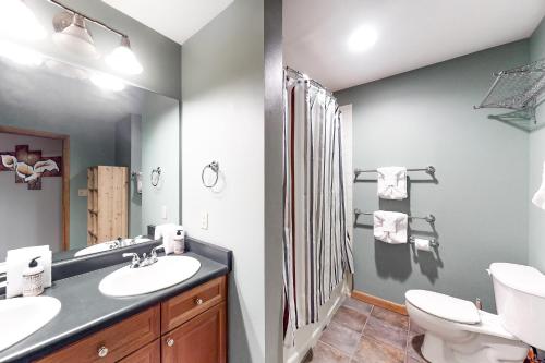ein Badezimmer mit einem Waschbecken, einem WC und einem Spiegel in der Unterkunft Ski In-Out Zephyr Mountain Lodge in Winter Park