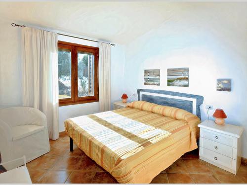 a bedroom with a bed and a chair and a window at La Sima villa con piscina vista mare San Pantaleo Sardegna in San Pantaleo