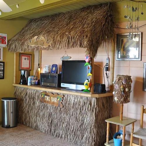 a bar with a television and a straw roof at Sea Aire Oceanfront Inn in Cocoa Beach