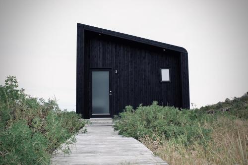 a black building with a wooden walkway leading to it at iStay Cottages in Sandgerði
