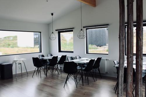 iStay Cottages في Sandgerði: غرفة طعام مع طاولات وكراسي ونوافذ