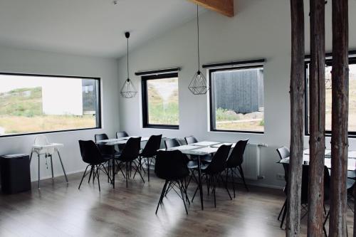 un comedor con mesas, sillas y ventanas en iStay Cottages, en Sandgerði