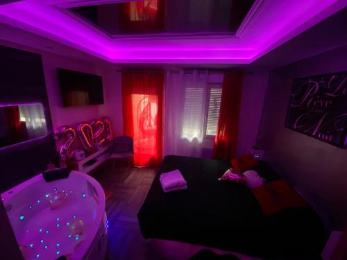 a room with purple lights and a bed and a tub at Le Rêve d'une Nuit suite Amour in Sarreguemines