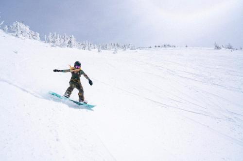 a person riding a snowboard down a snow covered slope at LOGE Bend in Bend