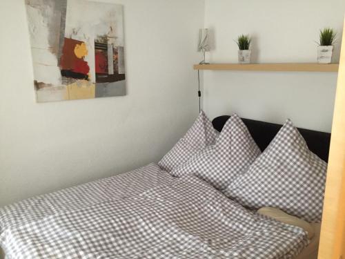ヴィリンゲンにあるFerienwohnungen Langのチェック入りのシーツと枕が付いたベッド
