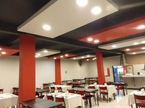 comedor con mesas y sillas blancas y vigas rojas en Hotel San Remo Majestic, en Mar de Ajó