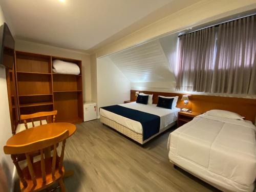 a bedroom with a bed and a desk and a table at Lapônia Hotel Gramado in Gramado