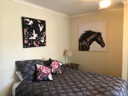 - une chambre avec un lit et une photo d'un cheval sur le mur dans l'établissement Bowral Bungalow, à Bowral