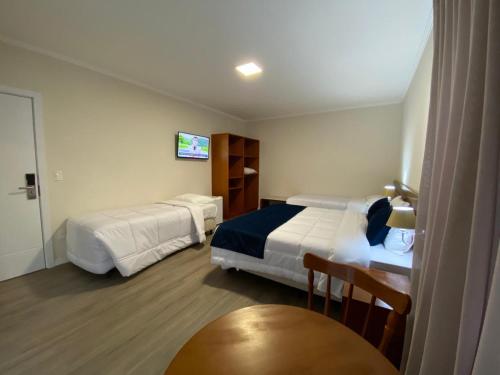 a hotel room with two beds and a table at Lapônia Hotel Gramado in Gramado