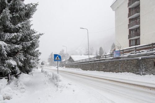 a snow covered street with a sign and a tree at Pragelato per chi ama la natura lo sci di fondo in Pragelato