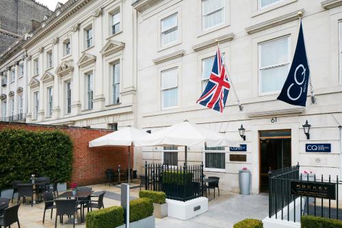 a hotel with tables and umbrellas in front of a building at Club Quarters Hotel Covent Garden Holborn, London in London