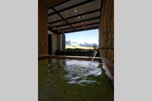 een zwembad met water in een kamer met een raam bij Casa Verano - 2 Hab 4 Baños Jacuzzi Rooftop A/C in Mérida