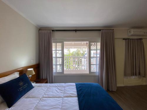 a bedroom with a bed with a blue pillow and a window at Lapônia Hotel Gramado in Gramado