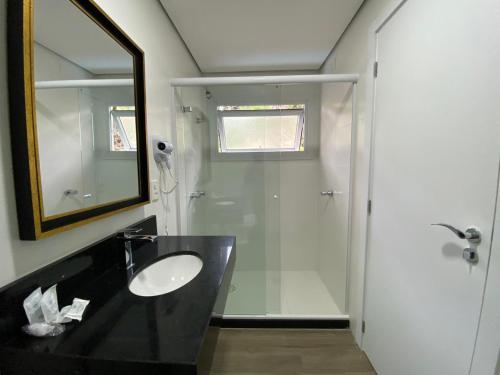 a bathroom with a sink and a mirror and a shower at Lapônia Hotel Gramado in Gramado