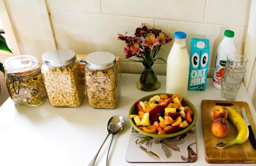 a counter with a bowl of fruit and jars of food at Magnolia House in Blenheim