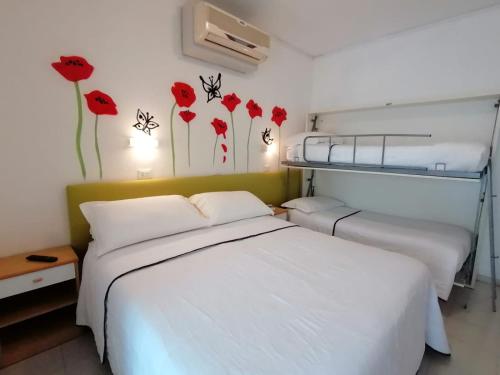 チェゼナーティコにあるKristalex Pet Family Hotelのベッドルーム1室(ベッド2台付)が備わります。壁には赤い花が飾られています。