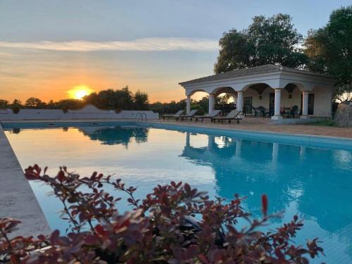 a swimming pool with a gazebo and the sunset at Quinta do Amauriz in Évora