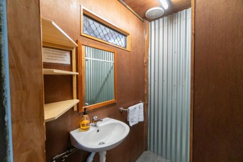 baño con lavabo, espejo y ventana en Woolshed Eco Lodge, en Hervey Bay