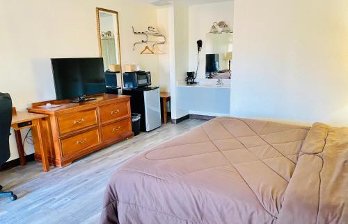a bedroom with a bed and a desk and a tv at Ozark Inn & Suites in Ozark