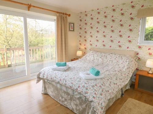 a bedroom with a bed and a balcony at Clovermead Cottage in Willington