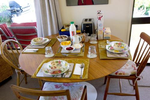 a wooden table with plates of food on it at Magnolia House in Blenheim