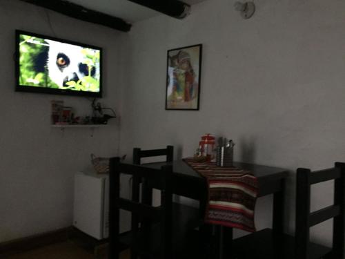 ein Esszimmer mit einem Tisch und einem TV an der Wand in der Unterkunft Asiriq Wasi Casita de huéspedes in Cusco
