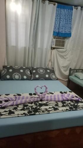 a bed with a purple and black blanket on it at Aloha in Oslob