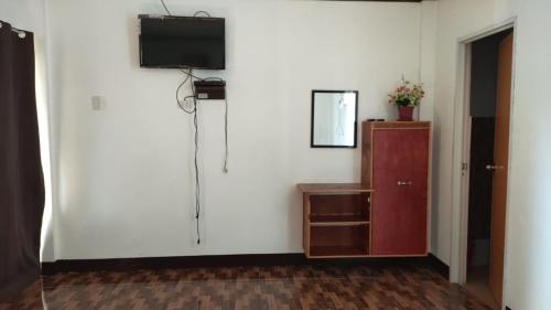 a room with a white wall with a tv and a cabinet at Aloha in Oslob
