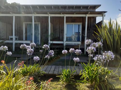 una casa de campo con flores púrpuras delante en Las Luciernagas Posada de Mar, en La Pedrera