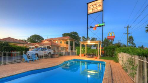 a swimming pool in front of a house with a sign at Country Roads Motor Inn in Goondiwindi
