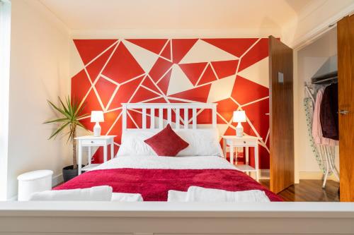 a bedroom with a white bed with a red wall at Avril Serviced Apartment in Birmingham