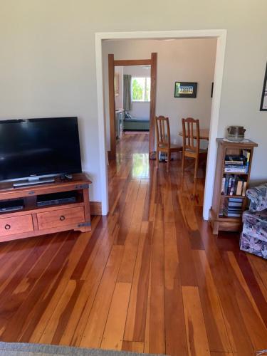 a living room with a flat screen tv and a wooden floor at One Panama in Martinborough 